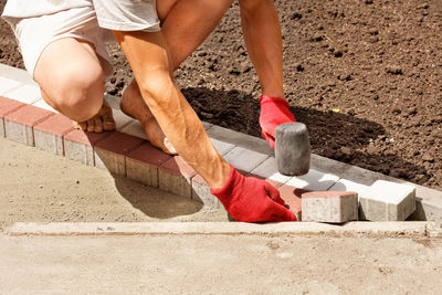 A young worker lays paving slabs on a bright sunny summer day on prepared sand base on the sidewalk