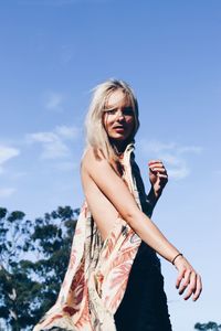 Low angle view of young woman standing against sky