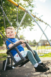 Young boy smiling and swinging at the park