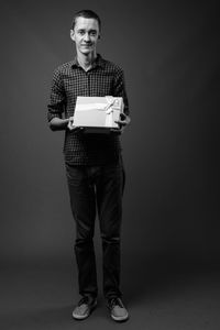 Portrait of young man standing against gray background