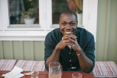 Portrait of smiling mid adult man sitting at table on porch