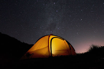 Tent on land against start field during night