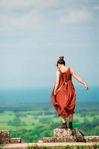 Rear view of young woman looking at sea while standing on observation point against sky