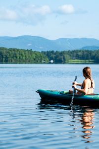 Man sitting on lake against sky