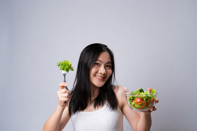 Portrait of woman holding ice cream against white background