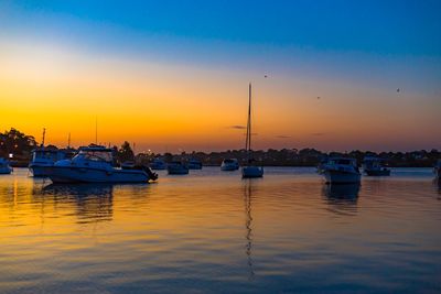 Sailboats moored in marina at sunset