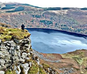 Rear view of man standing on cliff against sky