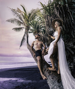 Young couple on tree trunk at beach