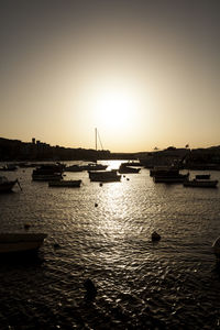 Boats in sea at sunset