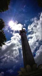 Low angle view of bird perching on statue against sky