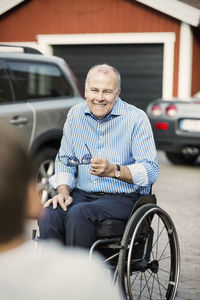 Happy father in wheelchair looking at son on street