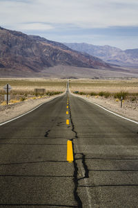 Empty road by mountains against sky