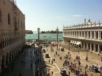 People walking along buildings with sea in background