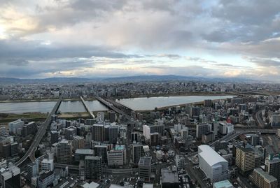 High angle view of city buildings against cloudy sky