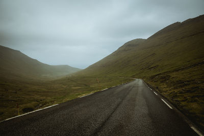 Empty road by mountains against sky