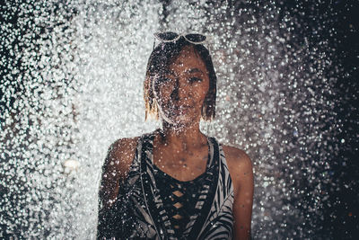 Portrait of woman standing outdoors at night during rainy season