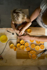 Boy making orange juice with father