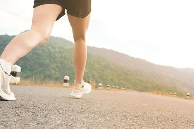 Low section of woman standing on road