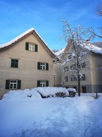 House on snow covered field against sky during winter