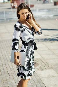 Midsection of woman holding smart phone while standing on street