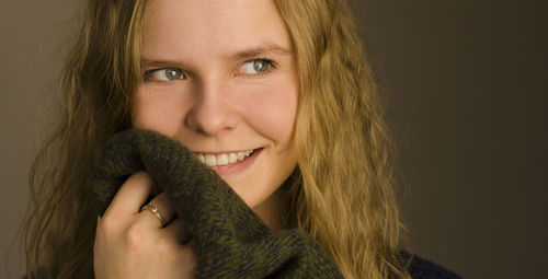 Close-up portrait of a smiling young woman over black background