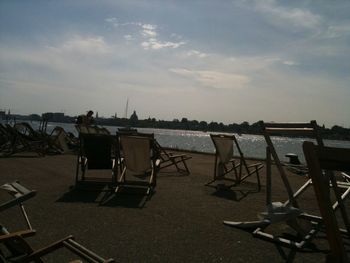 Chairs and table on beach against sky