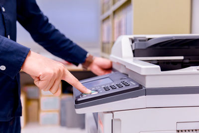 Midsection of businessman using photocopier in office