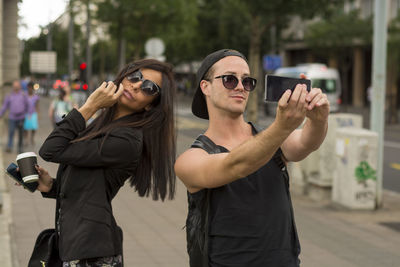 Young couple taking selfie on street through mobile phone