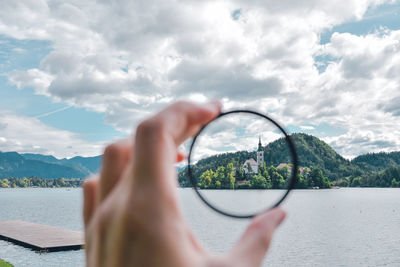 Midsection of person holding lake against sky