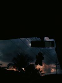 Silhouette palm trees against sky seen through car windshield