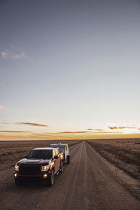 Cars on road against sky during sunset