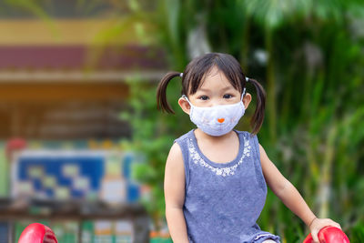 Portrait of cute girl wearing mask standing outdoors