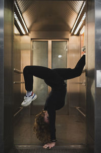 Side view of woman doing handstand at doorway