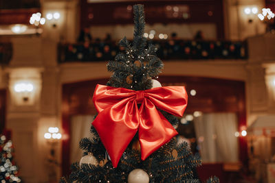 Red silky bow hanging on christmas tree. beautiful christmas decor. winter holiday and new year