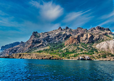 Scenic view of sea and mountains against blue sky