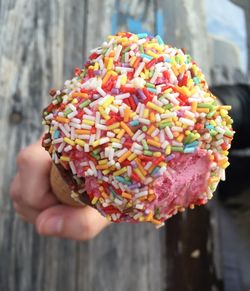 Cropped hand holding ice cream cone with sprinkles