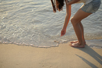 Low section of woman bending at beach