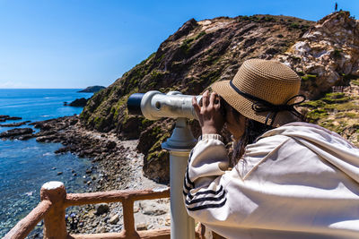 Rear view of woman photographing sea against clear blue sky