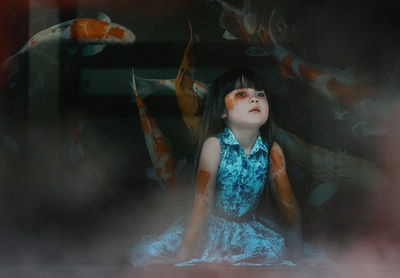 Digital composite image of girl against koi fish