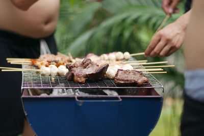 Midsection of man preparing meat on barbecue grill