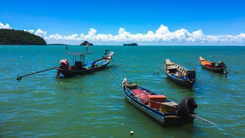 Boats moored in sea against blue sky