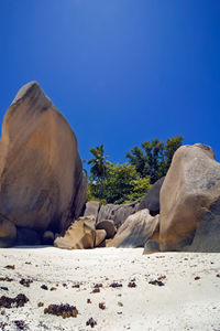 Rocks on sand against clear blue sky