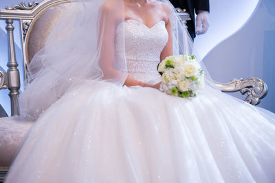 Midsection of bride holding bouquet