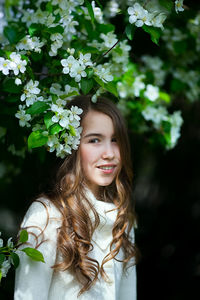 Portrait of cute girl standing by flowering plant outdoor
