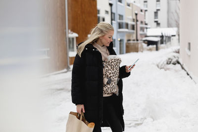 Woman with baby in carrier using cell phone