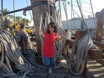 Smiling young woman sitting on rope against built structure