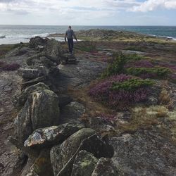 Rear view of man walking on beach against sky