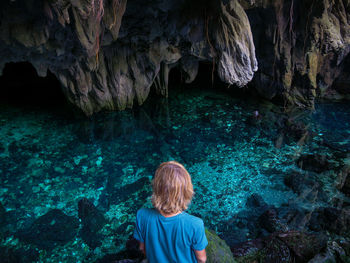 Rear view of woman standing on rock in cave