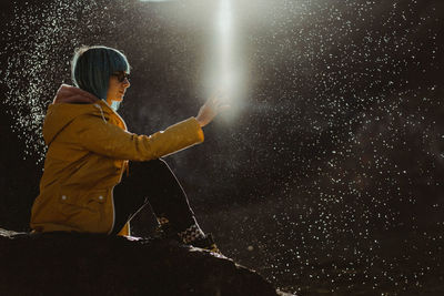 Side view of woman holding umbrella at night