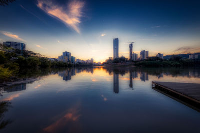 Reflection of illuminated buildings in city against sky